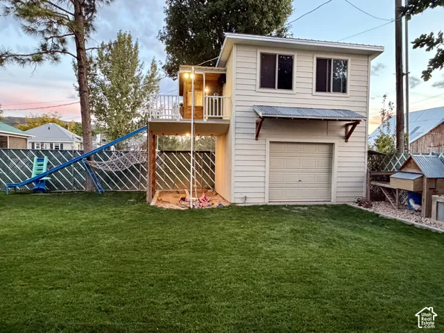 Expansive grassy backyard with a two-story shed/storage/workshop featuring a garage door and upper windows.