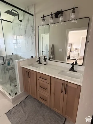 Dual vanity with wood-finish cabinetry, white countertops, and matte black fixtures
