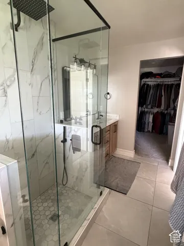 Glass-enclosed shower with a rainfall showerhead, white marble-finish tile, and a hexagonal tile floor