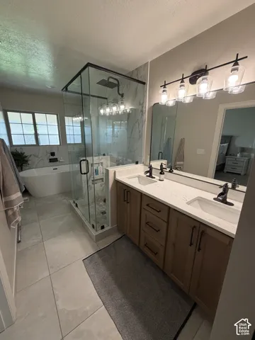 Master bath. Dual vanity with light wood-finish cabinetry and white countertops
