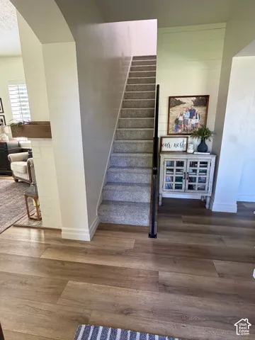 Wood-finish flooring, carpeted staircase, and decorative wall paneling