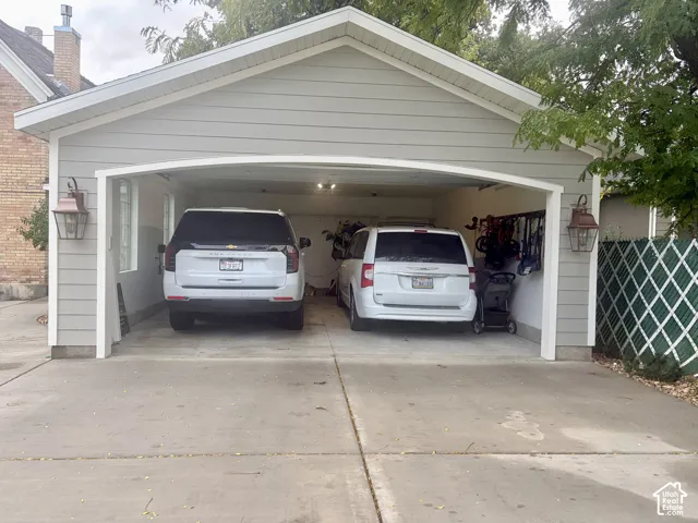 Garage featuring light-colored siding, dual overhead lighting, and two decorative exterior lanterns