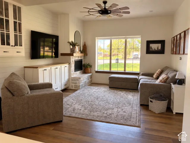 Wood-finish flooring throughout, a stone-clad fireplace, and a large window providing ample natural light