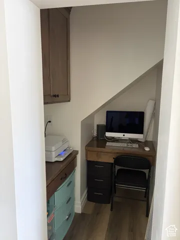 Built-in wood-finish cabinet, wood-finish countertop, wood-finish flooring, and white baseboards