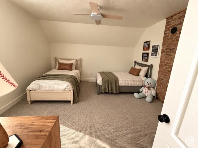 Exposed brick accent wall with potential for wood stove, neutral carpeting, sloped ceilings, ceiling fan, and white trim