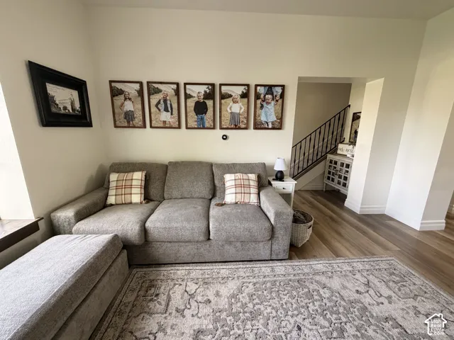 Light wood-finish flooring, white baseboards, and a staircase featuring a black metal railing
