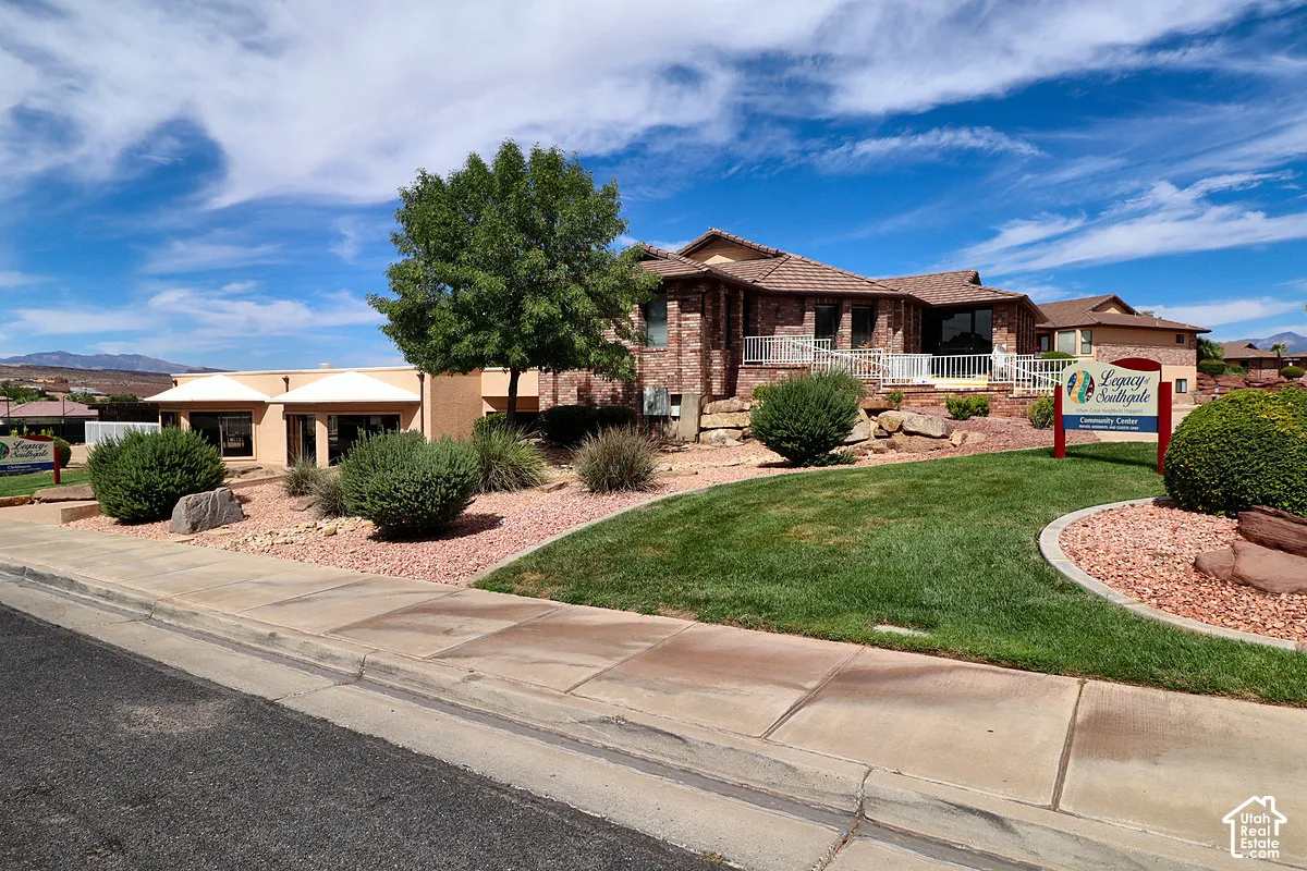 Brick exterior with multiple windows, terraced landscaping, concrete sidewalks, and a manicured lawn