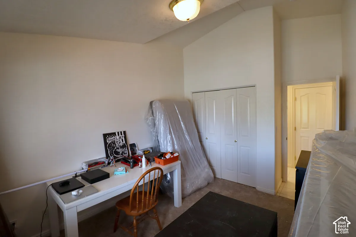 Carpeted flooring, vaulted ceiling, bi-fold closet doors, and recessed ceiling light fixture