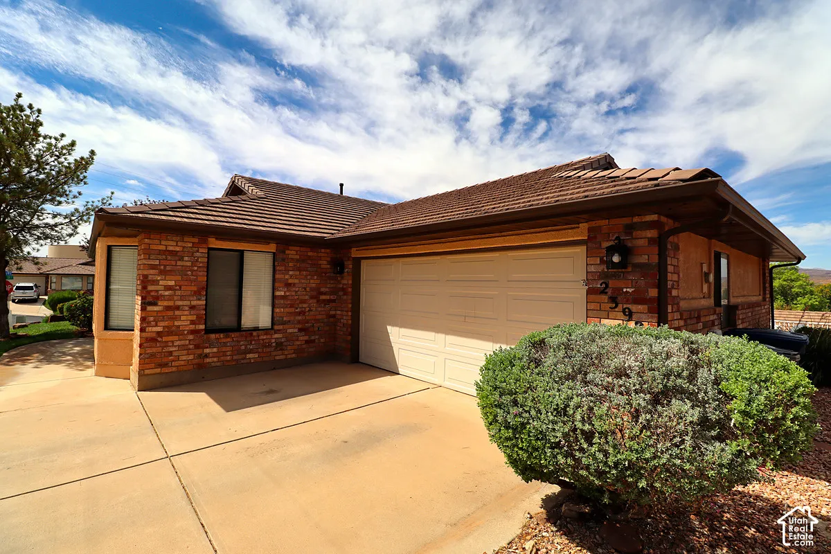 Brick exterior with a tile roof, an integrated garage, and a concrete driveway