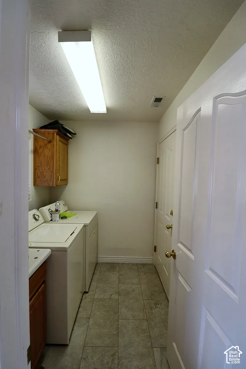 Utility area featuring tiled flooring, a built-in wood-finish cabinet, and a panel door