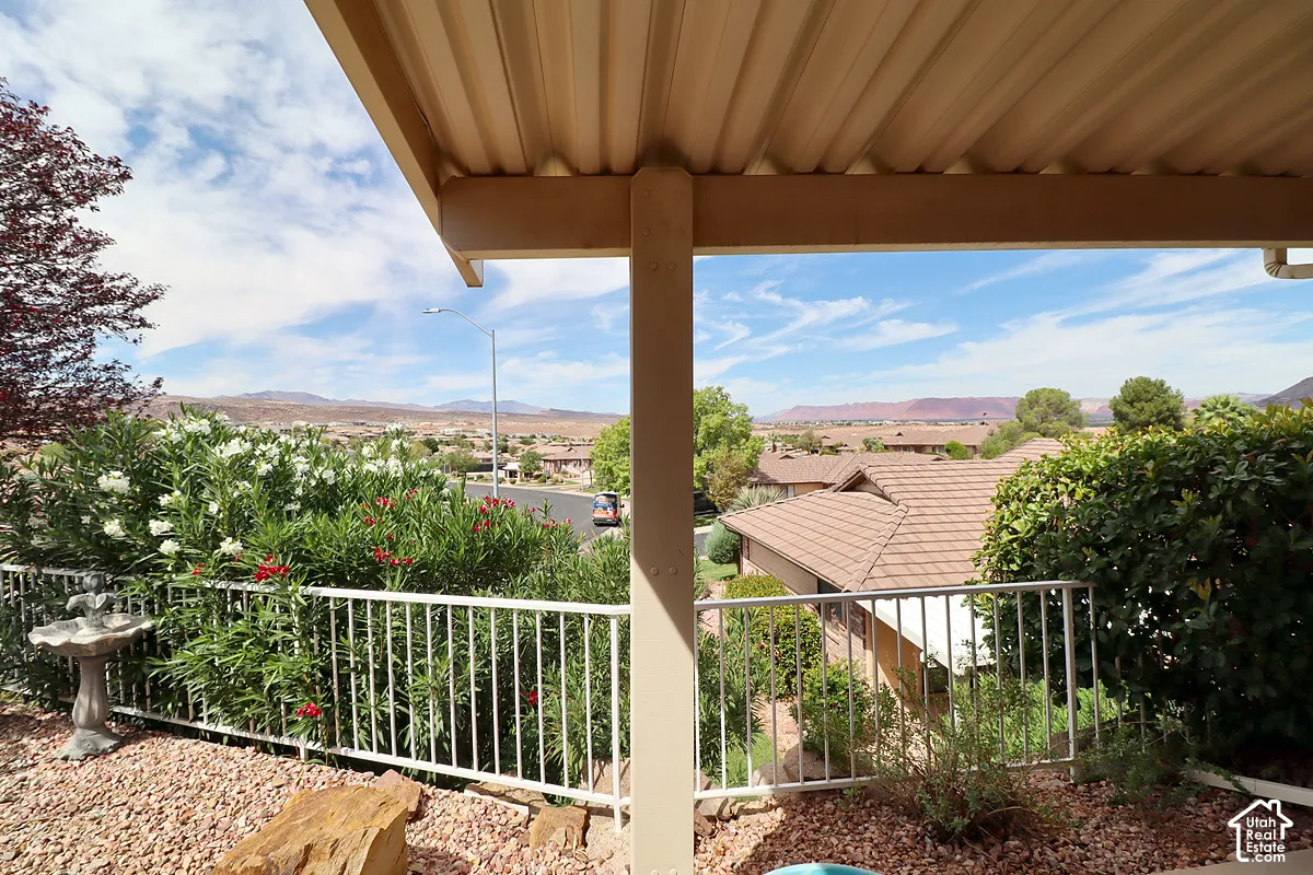 Covered patio with a corrugated roof structure, white metal railing, and rock landscaping