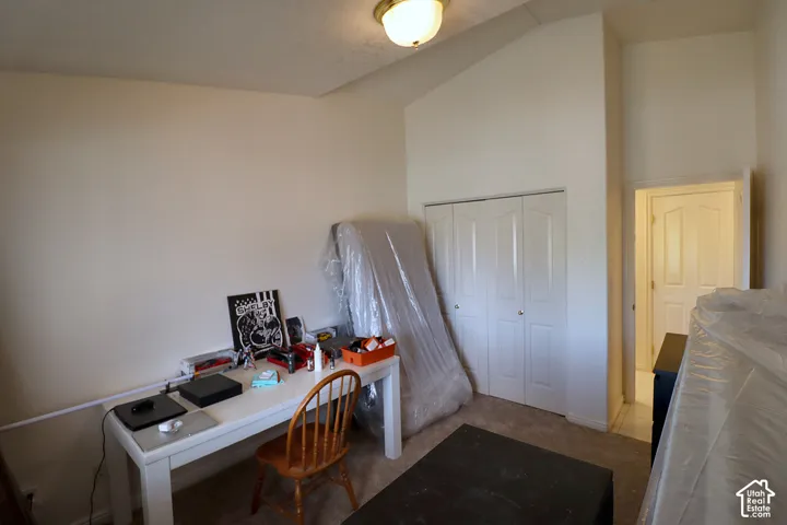 Carpeted flooring, vaulted ceiling, bi-fold closet doors, and recessed ceiling light fixture