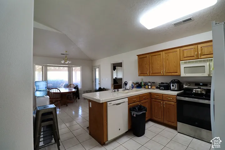 Open-concept kitchen and dining area featuring tile flooring, wood-finish cabinetry, built-in microwave, and a bay window in the dining space