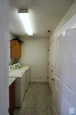 Utility area featuring tiled flooring, a built-in wood-finish cabinet, and a panel door
