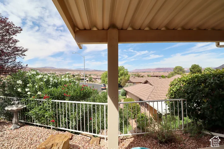 Covered patio with a corrugated roof structure, white metal railing, and rock landscaping