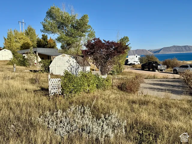 Scenic acreage featuring native landscaping with drought-resistant plantings, mature trees, and distant water vistas