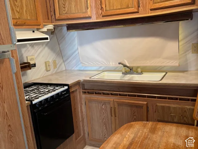 Wood-finish cabinetry, built-in gas range, integrated sink, and a wood-finish dining surface