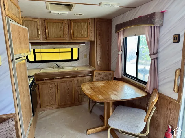 Integrated galley kitchen with wood-finish cabinetry, stainless steel sink, and compact refrigerator