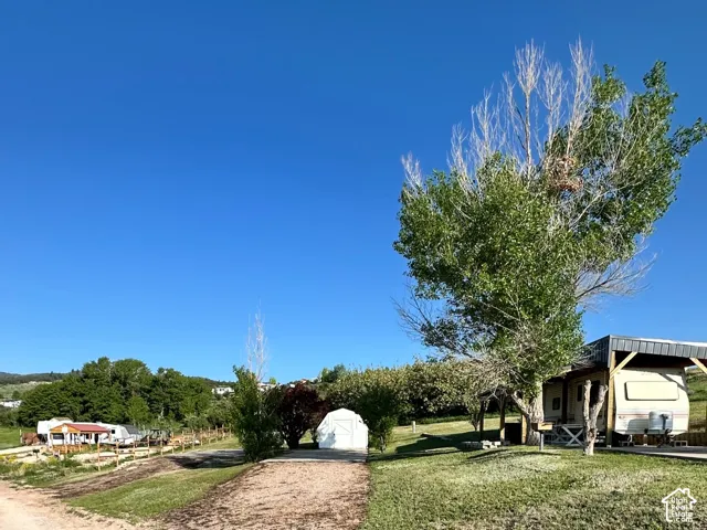 Expansive property featuring a gravel path, mature trees, and a covered structure