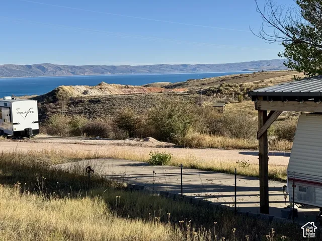 Expansive outdoor area featuring a lake and mountain backdrop, a covered structure with a metal roof, with conrete driveway on lot 161