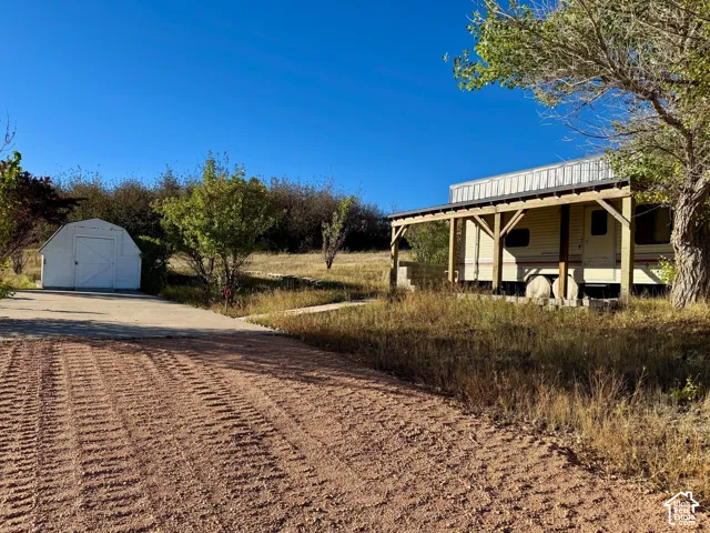 Gravel driveway to concrete parking leading to shed and natural landscaping lot 160