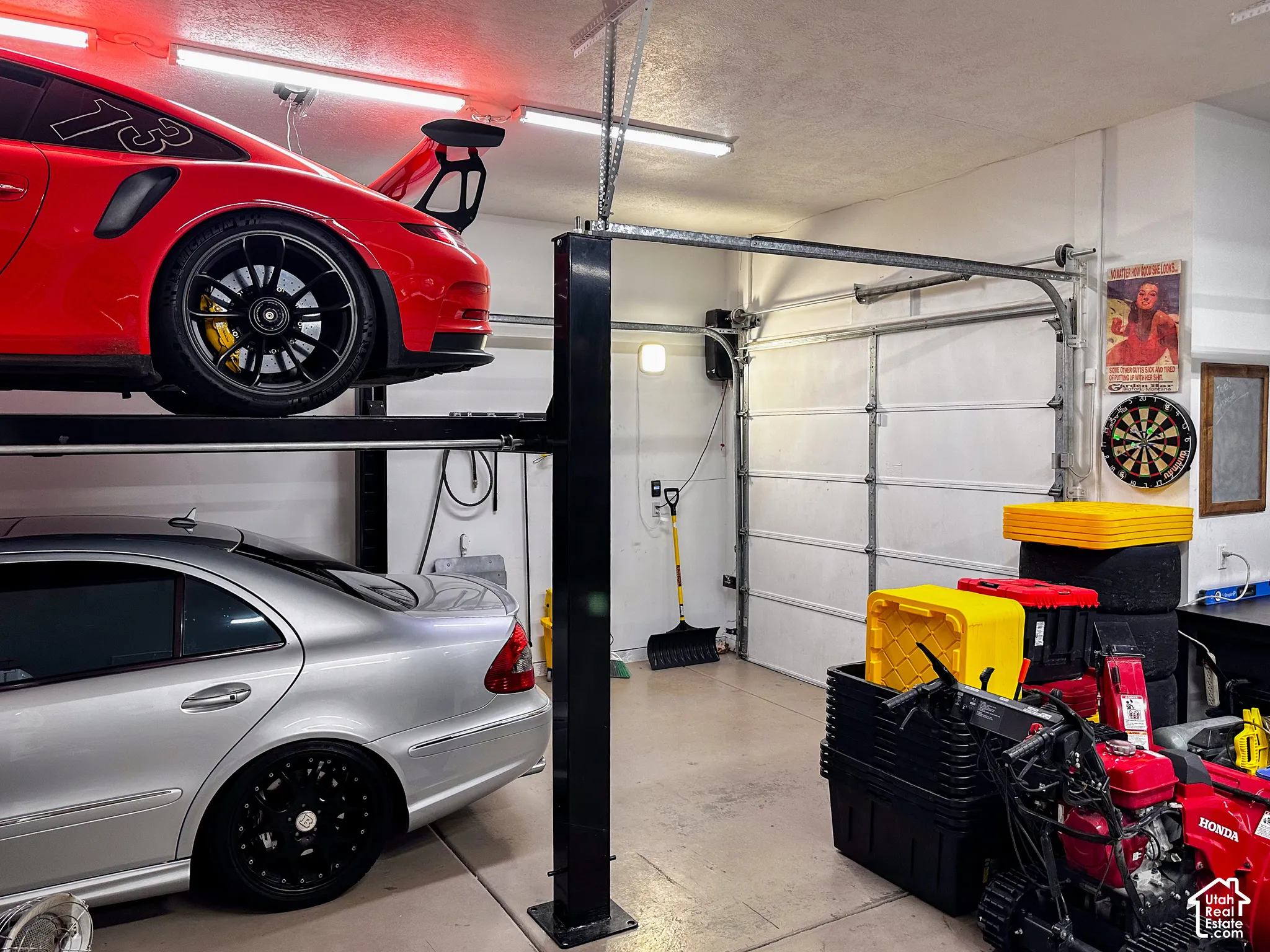 Garage with a multi-car lift system, overhead lighting, and a roll-up door