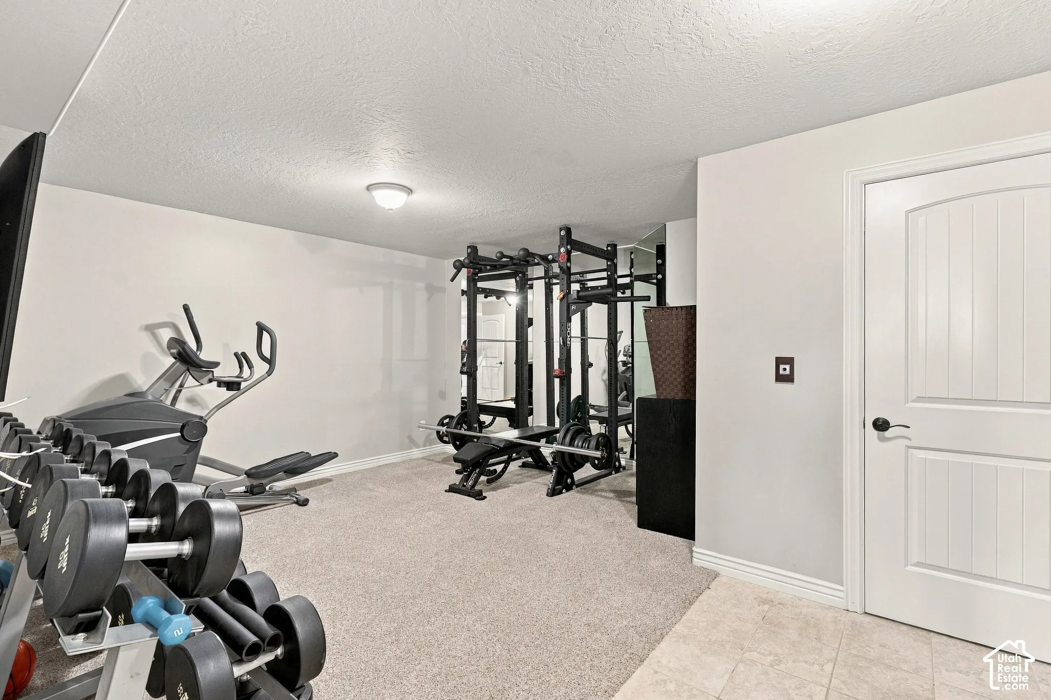 Carpeted flooring, recessed ceiling light, white paneled door with dark hardware, light gray wall paint, and ceramic tile flooring