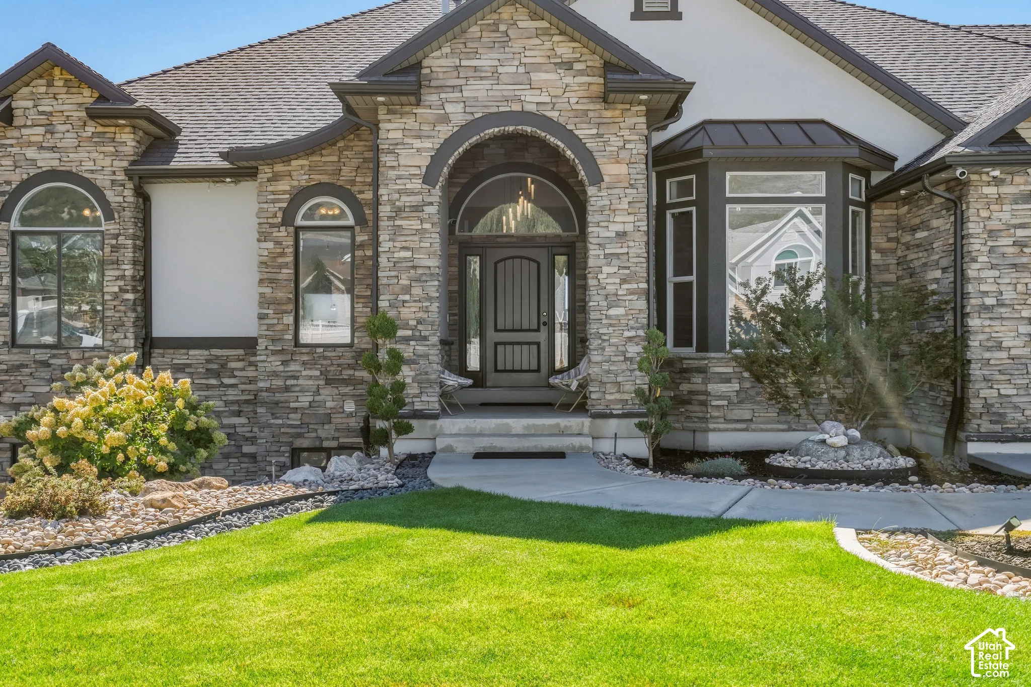 Stone veneer exterior featuring an arched entryway and a bay window
