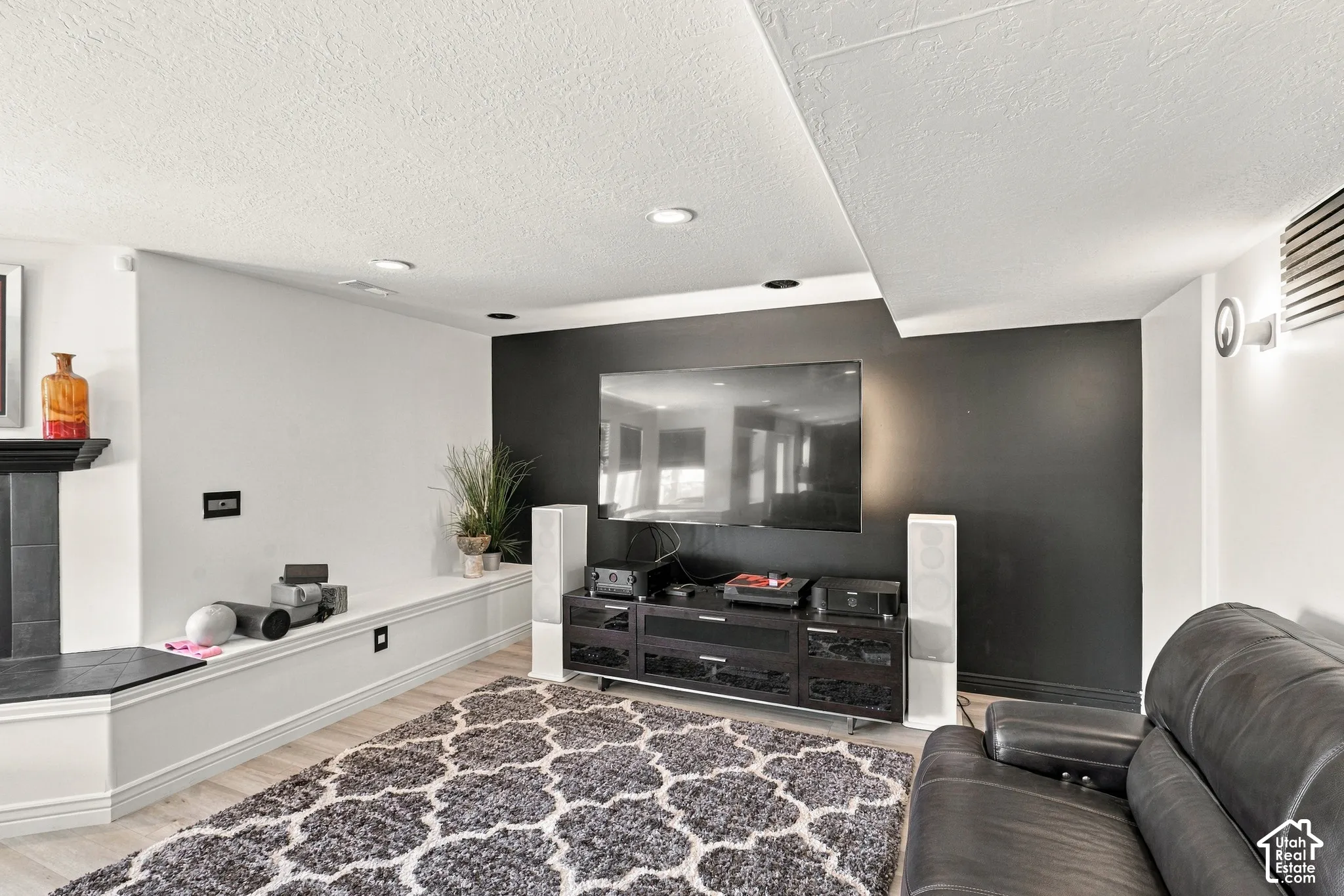 Light wood-finish flooring, recessed ceiling lighting, a built-in bench, and a dark accent wall