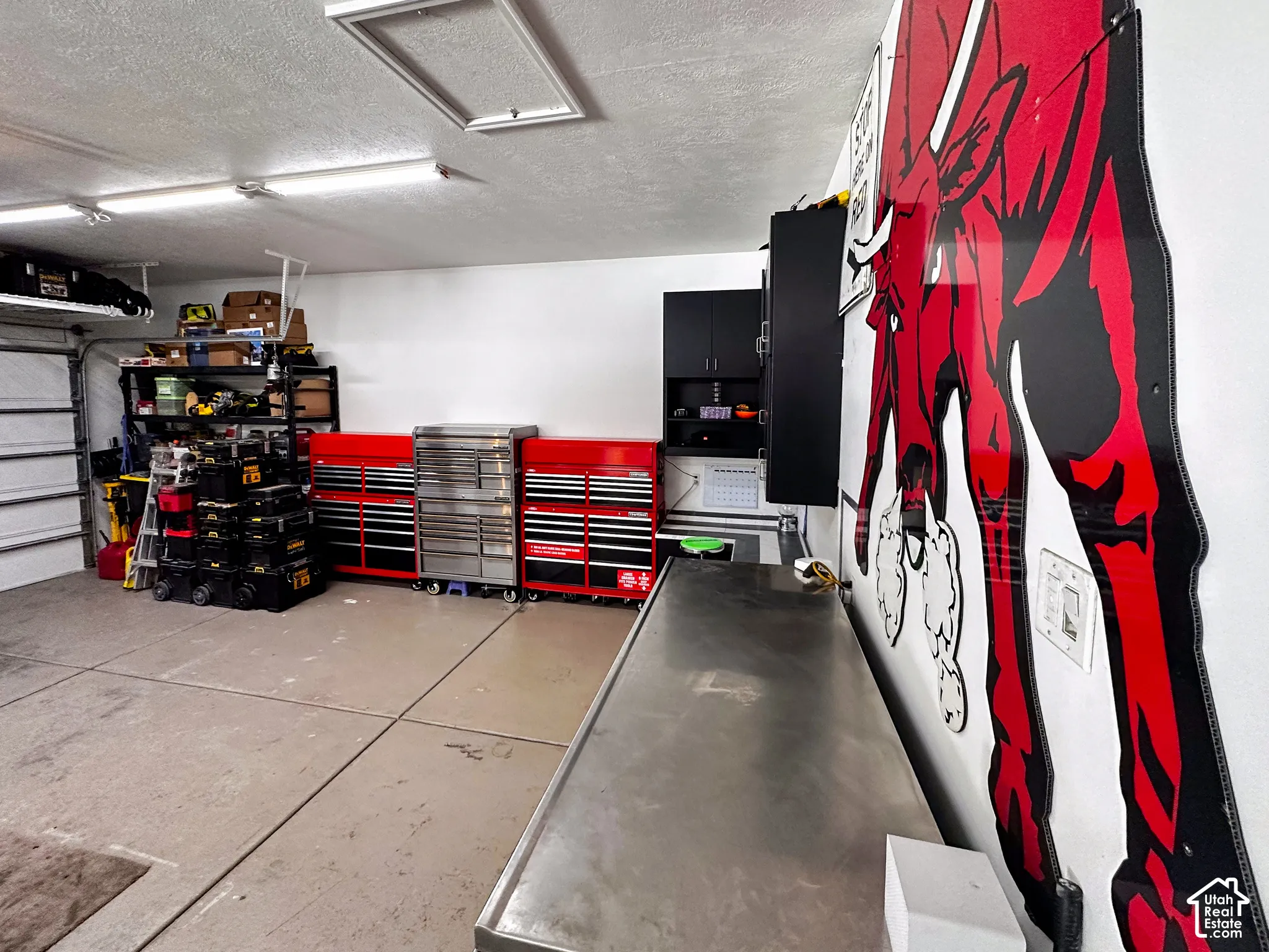 Concrete flooring with painted finish, recessed lighting, wall-mounted cabinetry, and built-in work surface