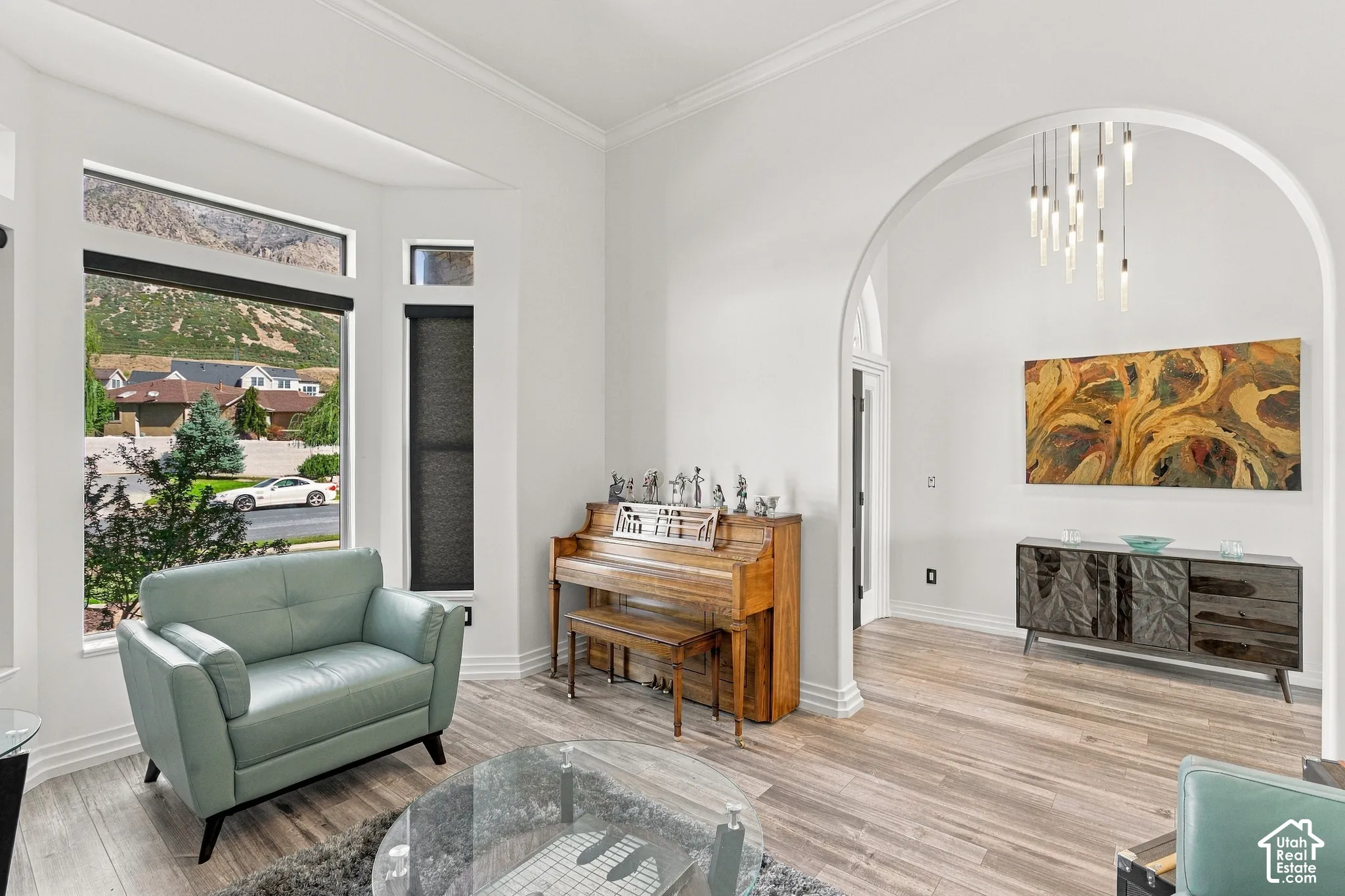 Bright living area featuring wood-finish flooring, a prominent arched doorway, and ample natural light through multiple windows