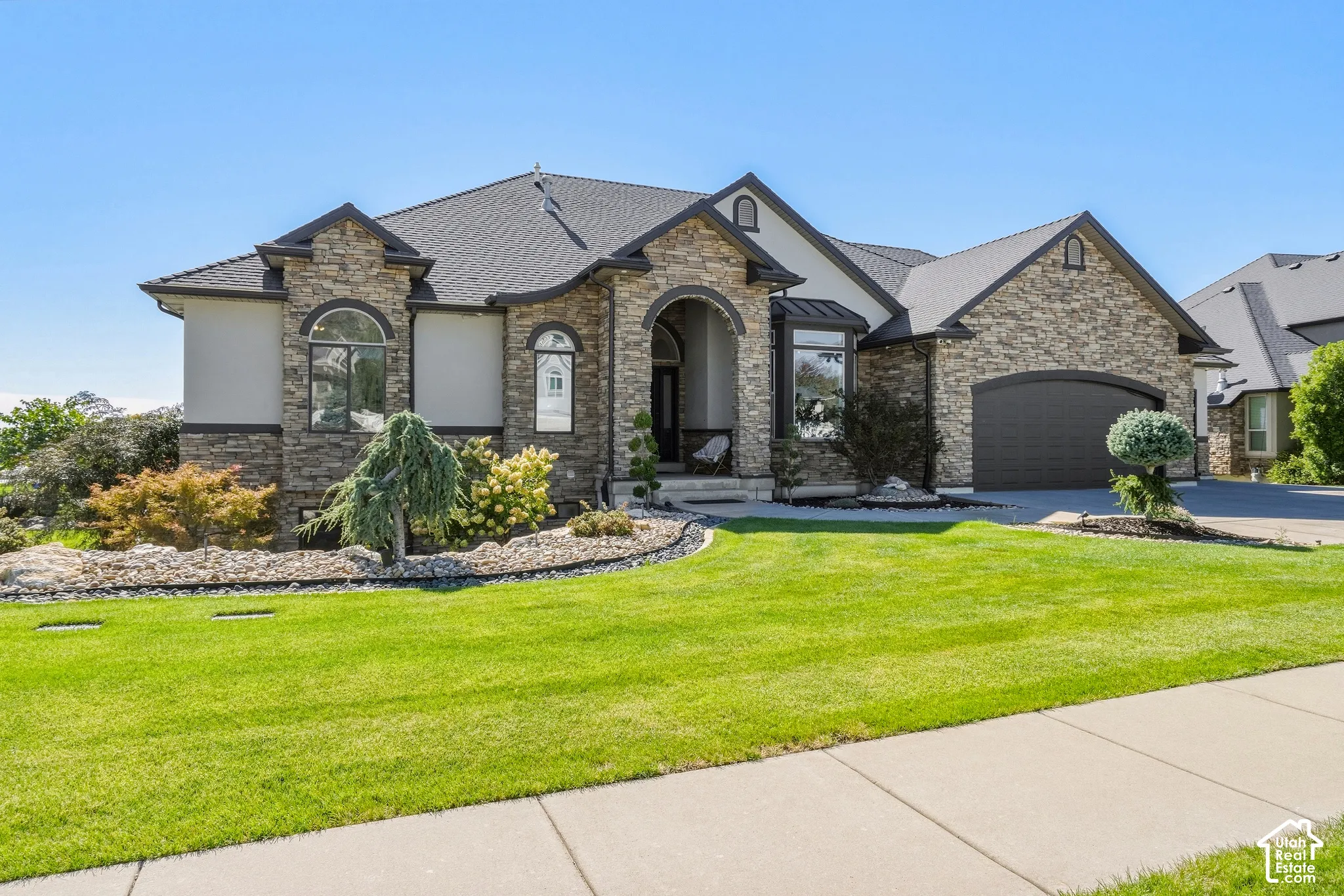 Striking stone and stucco exterior with arched entryways and multiple gables