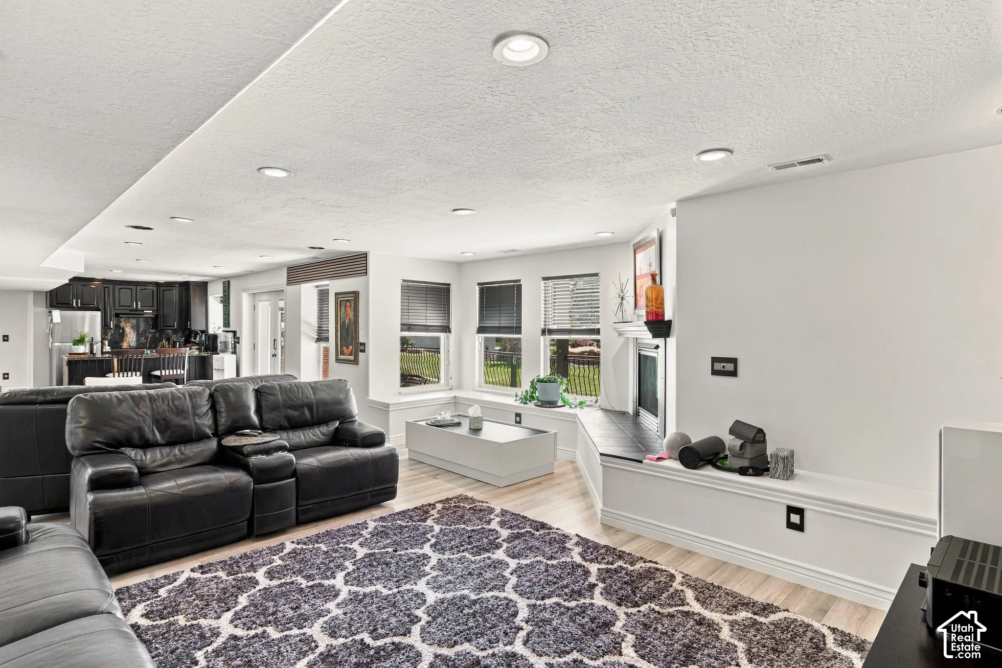 Recessed lighting illuminates the open-concept living space with wood-finish flooring