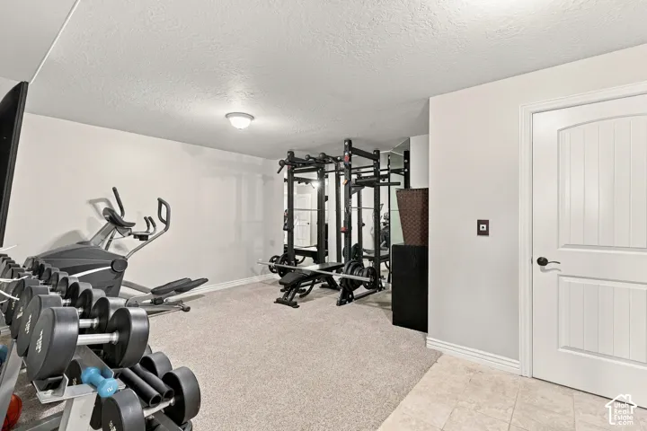 Carpeted flooring, recessed ceiling light, white paneled door with dark hardware, light gray wall paint, and ceramic tile flooring