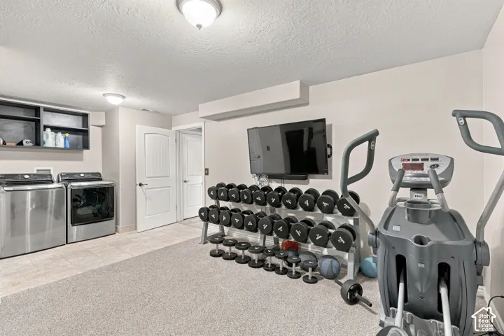 Finished basement recreation space featuring neutral tile flooring, recessed ceiling lighting, and a wall-mounted flat-screen television