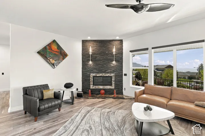 Stacked stone fireplace with a stone mantel, wood-finish flooring, and expansive windows