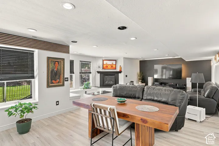 Recessed lighting, wood-finish flooring, multiple windows with black blinds, built-in fireplace, and a dark accent wall