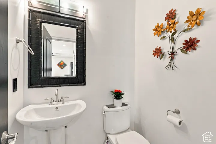 Pedestal sink with chrome faucet, framed mirror, and wall-mounted lighting fixture