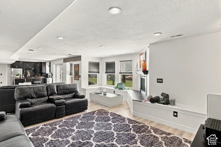 Recessed lighting illuminates the open-concept living space with wood-finish flooring