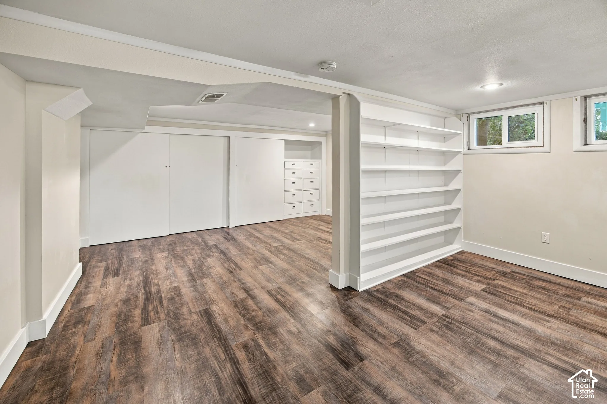 Wood-finish flooring, built-in shelving, recessed lighting, and sliding closet doors