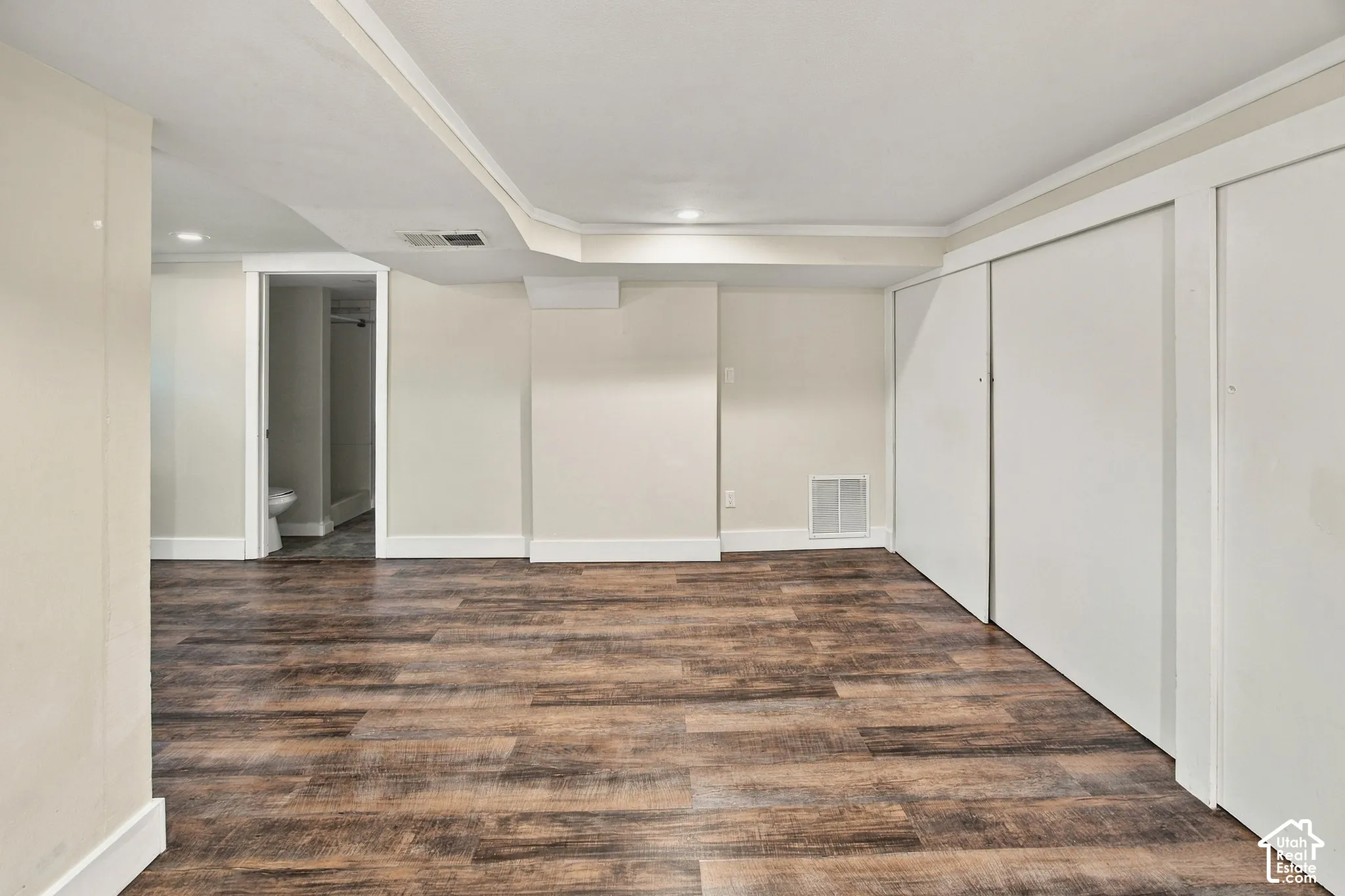 Wood-finish flooring, recessed lighting, white trim, and sliding closet doors