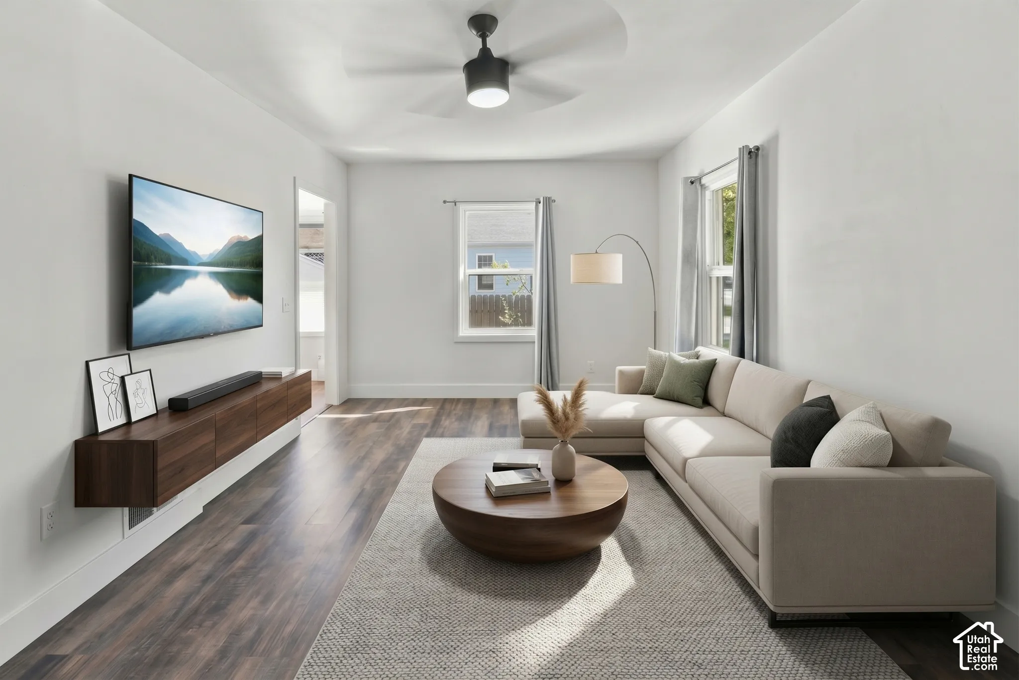 Wood-finish flooring throughout, bright white walls, and a ceiling fan with integrated lighting