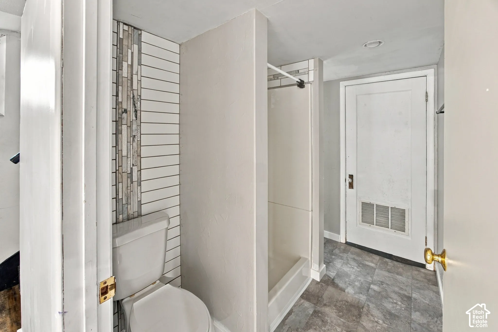 Full bath featuring a white toilet, subway tile accent wall, and a shower with a white surround