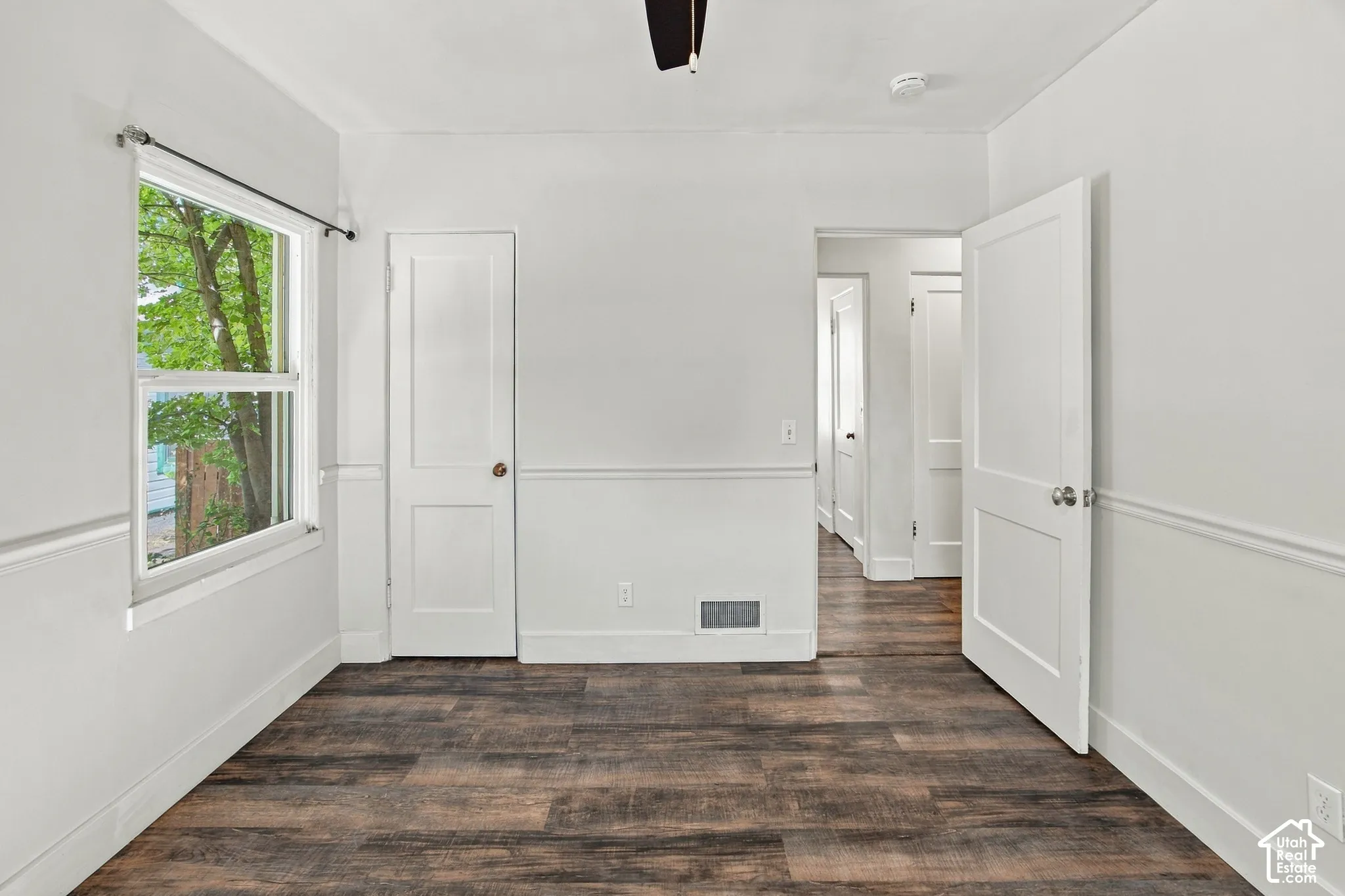 Wood-finish flooring, white paneled walls with chair rail molding, and white trim throughout