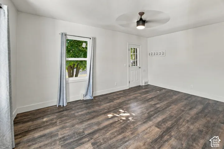 Wood-finish flooring, white walls, ceiling-mounted fan, white paneled door, and a white framed window