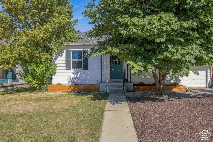 White siding exterior with a teal entry door, complemented by dark shutters and a white garage door