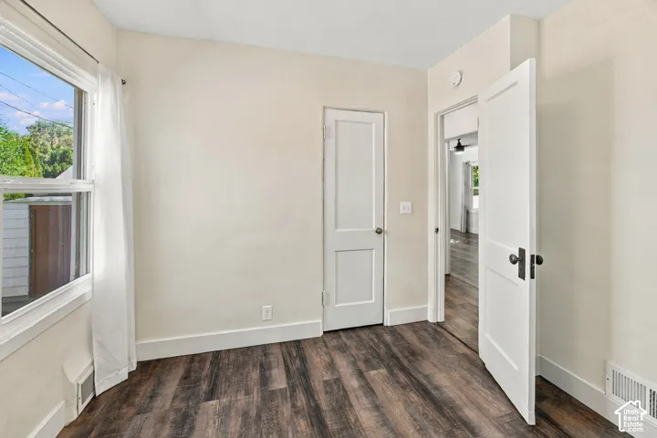 Wood-finish flooring throughout, white trim, and a white interior door