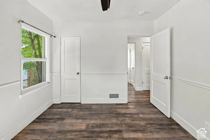 Wood-finish flooring, white paneled walls with chair rail molding, and white trim throughout