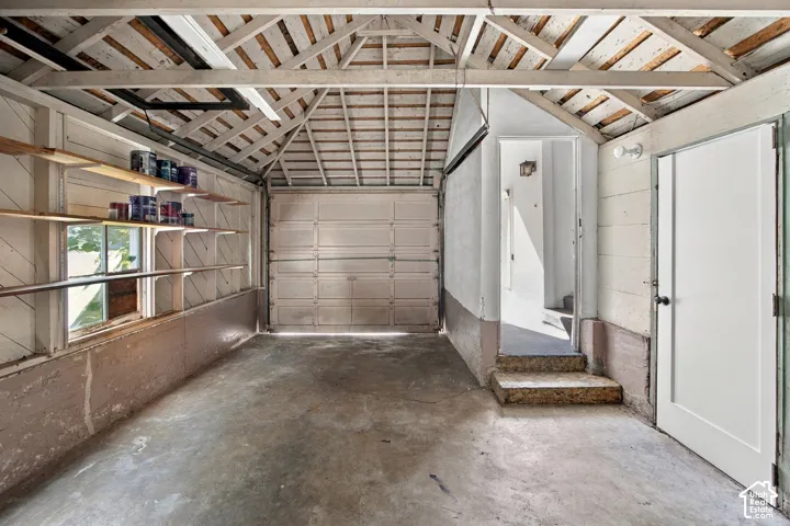 Spacious garage featuring a concrete floor, built-in shelving, and a pedestrian door for interior access