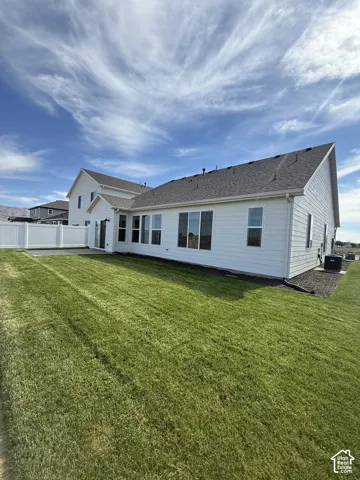 Rear of home, featuring full yard landscaping and partial fence